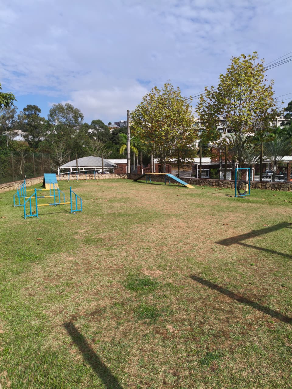 Espaço pet com circuito de agility ao ar livre cercado por mata nativa