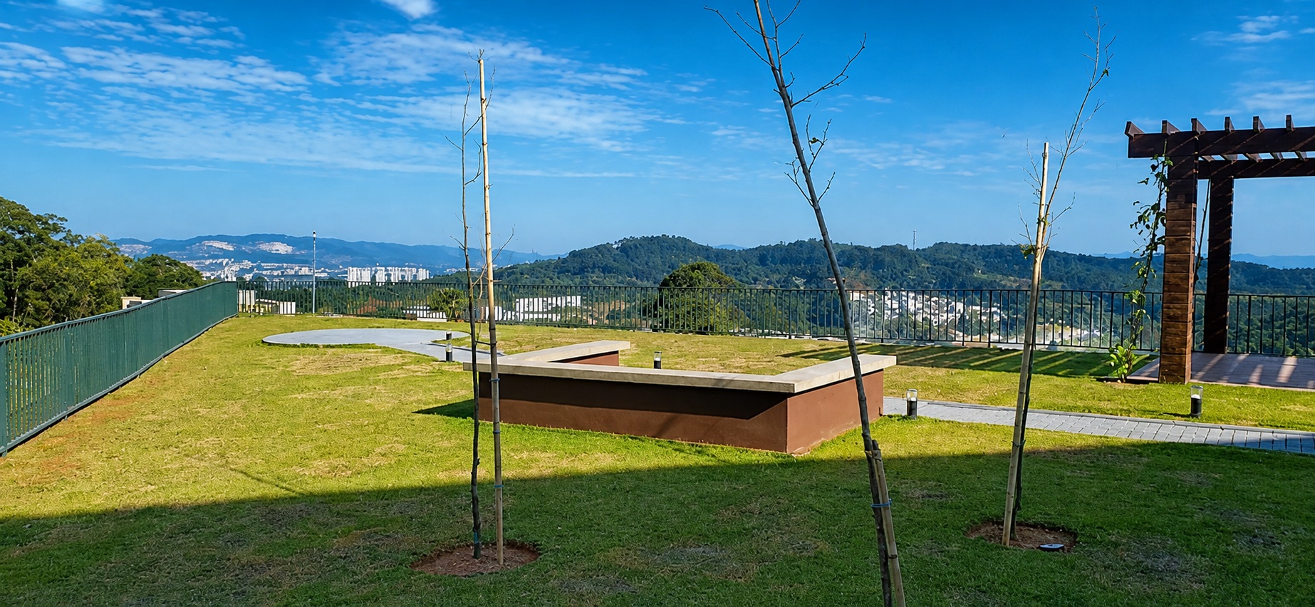 Área do Mirante com bancos de concreto, pergolado e paisagismo, com vista panorâmica para a região