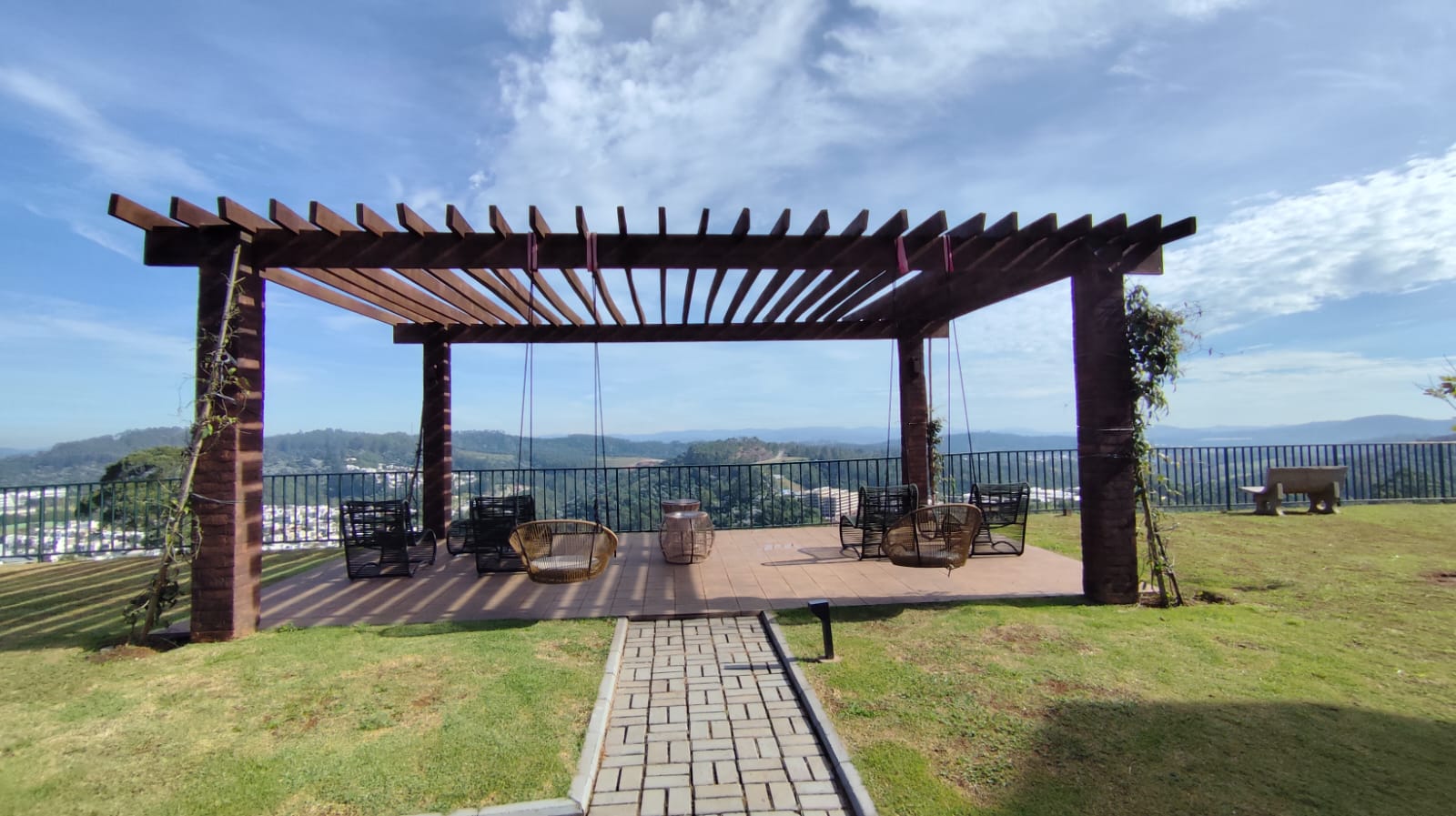 Pergolado de madeira do Mirante com cadeiras de balanço suspensas e vista panorâmica para as montanhas