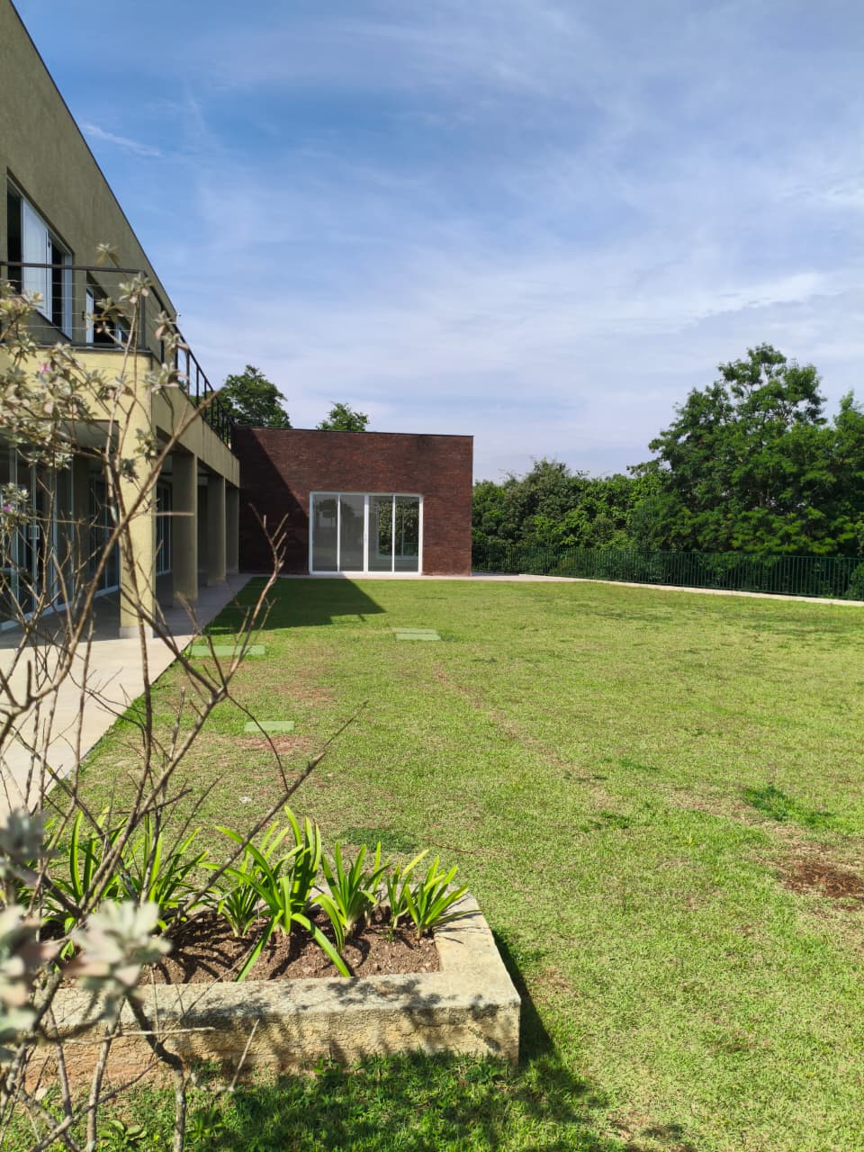 Vista ampla do Salão de Festas e do anexo em tijolinho, com o gramado do residencial